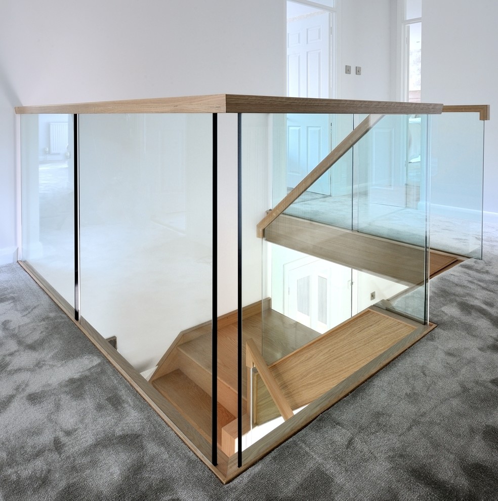 Photo of a mid-sized traditional wood curved staircase in Buckinghamshire with glass risers and wood railing.