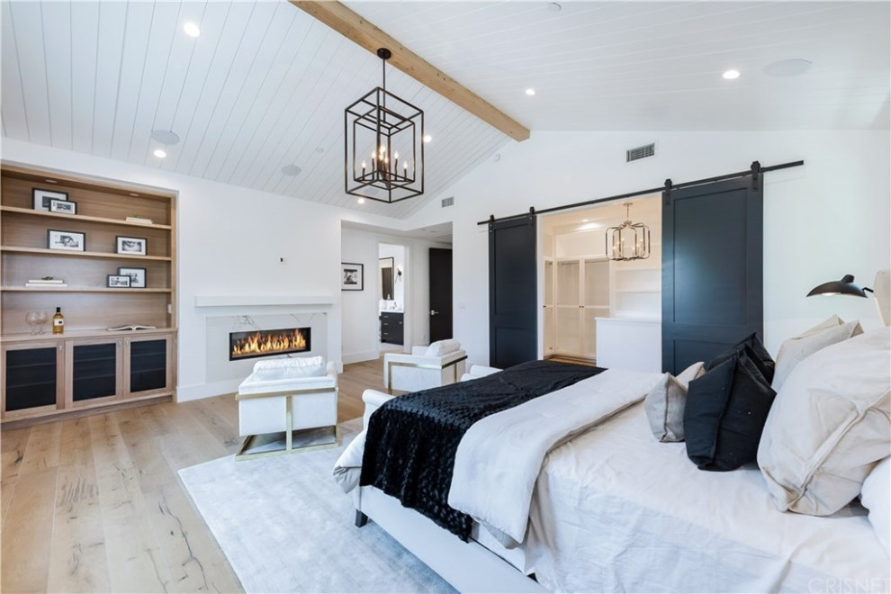 Großes Modernes Hauptschlafzimmer mit weißer Wandfarbe, hellem Holzboden, Gaskamin, Kaminumrandung aus Stein, braunem Boden und Holzdielendecke in Los Angeles
