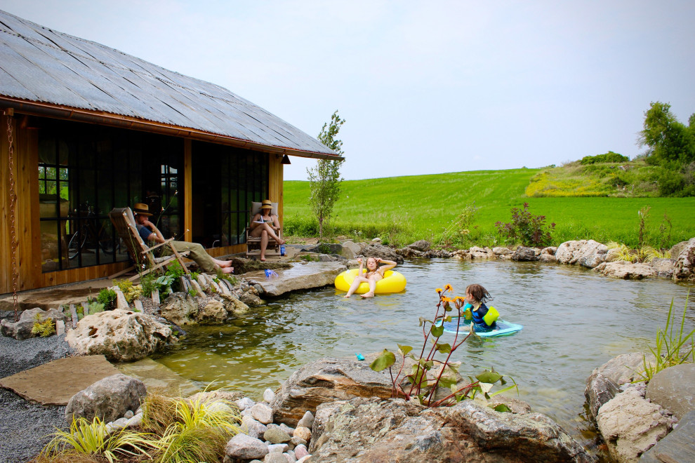 Aménagement d'un grand piscine avec aménagement paysager scandinave en forme de haricot avec une cour et des pavés en pierre naturelle.