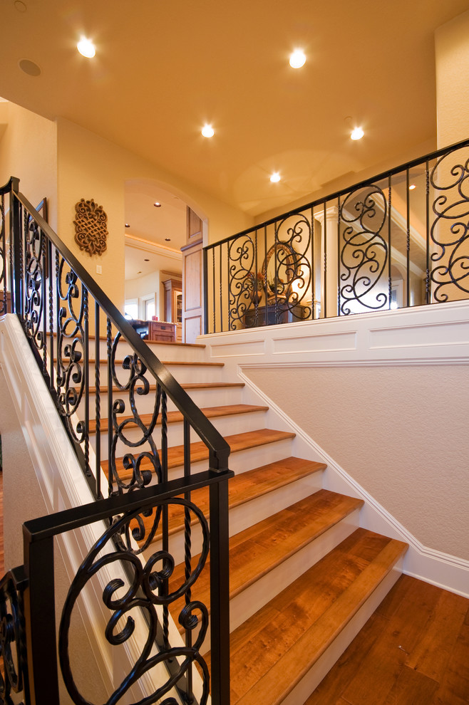 Mid-sized mediterranean wood curved staircase in Portland with painted wood risers and metal railing.