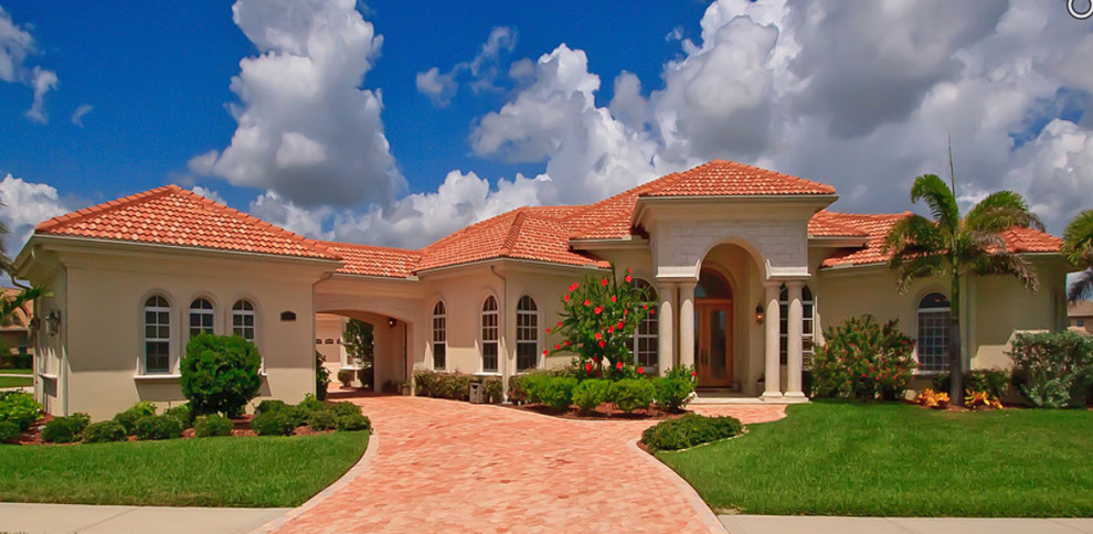 Inspiration for a mid-sized mediterranean one-storey stucco beige house exterior in Orlando with a hip roof and a tile roof.