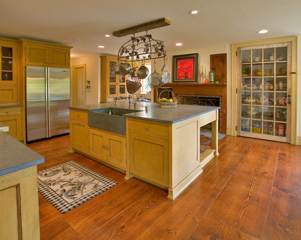 Large country u-shaped kitchen pantry in New York with a farmhouse sink, recessed-panel cabinets, distressed cabinets, soapstone benchtops, stainless steel appliances, medium hardwood floors and with island.