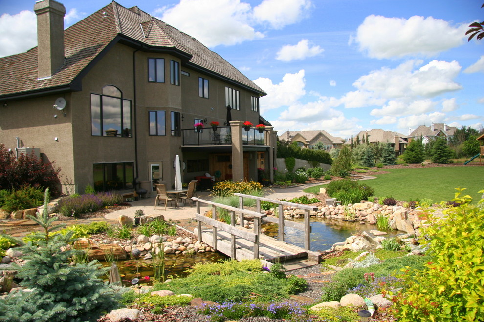 Photo of a country backyard full sun garden in Edmonton with a water feature and brick pavers.