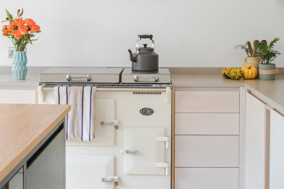 Medium sized contemporary l-shaped open plan kitchen in Oxfordshire with a built-in sink, flat-panel cabinets, engineered stone countertops, stainless steel appliances, medium hardwood flooring, an island, brown floors and beige worktops.