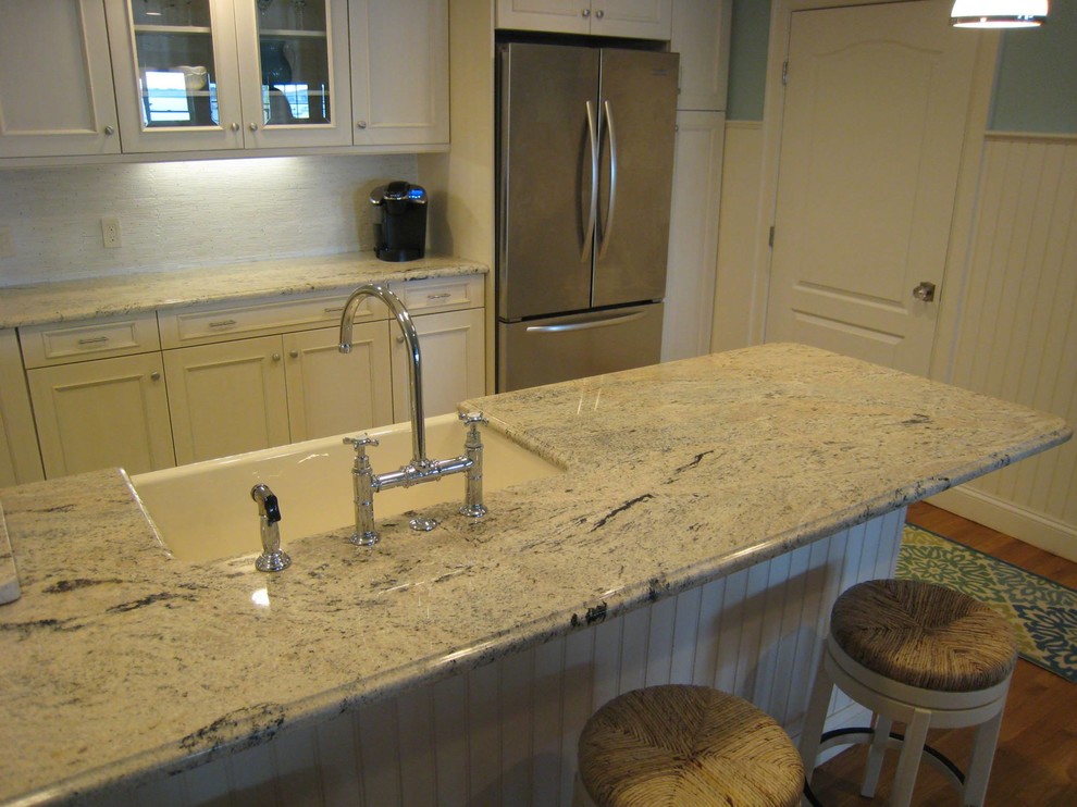 Mid-sized transitional u-shaped medium tone wood floor and brown floor open concept kitchen photo in Providence with a farmhouse sink, recessed-panel cabinets, white cabinets, granite countertops, white backsplash, ceramic backsplash, stainless steel appliances, a peninsula and gray countertops
