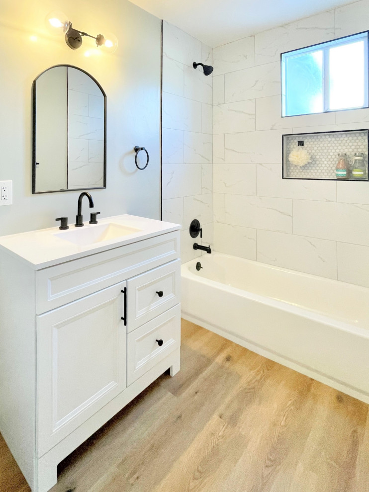 This is an example of a small modern bathroom in San Diego with shaker cabinets, white cabinets, an alcove bath, an alcove shower, a two-piece toilet, white tiles, porcelain tiles, green walls, vinyl flooring, an integrated sink, engineered stone worktops, beige floors, a shower curtain, white worktops, a wall niche, a single sink and a freestanding vanity unit.