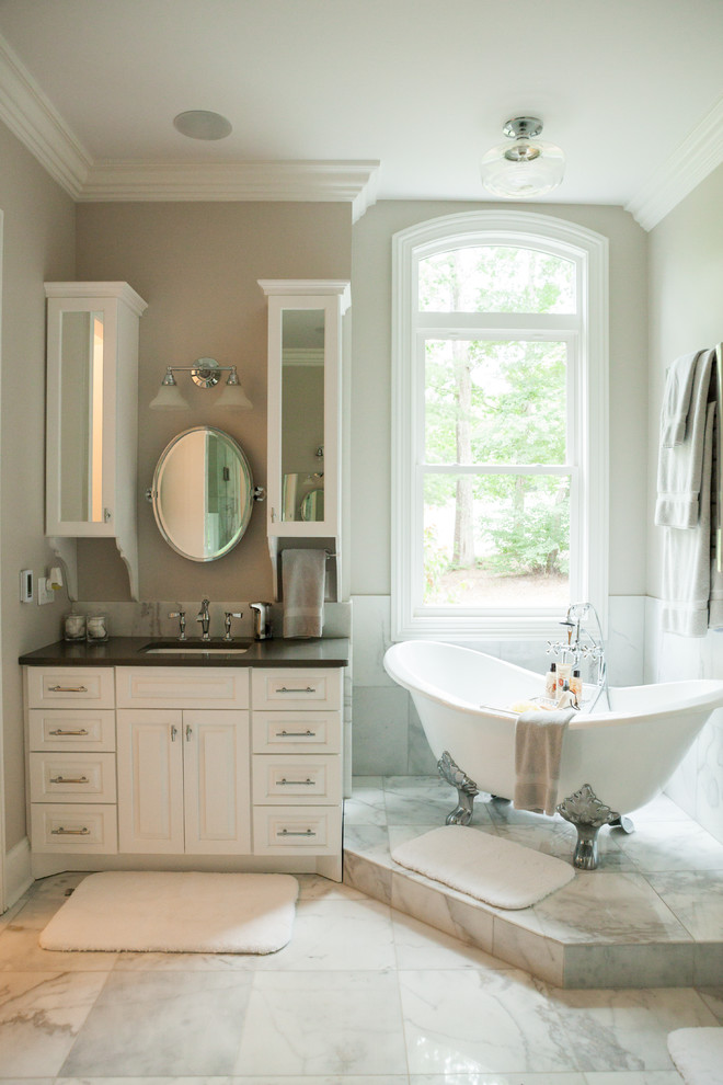 Design ideas for a small traditional master bathroom in Charlotte with gray tile, raised-panel cabinets, white cabinets, a claw-foot tub, stone tile and beige walls.