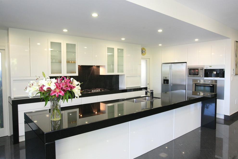This is an example of a contemporary kitchen in Brisbane with white cabinets, granite benchtops and with island.