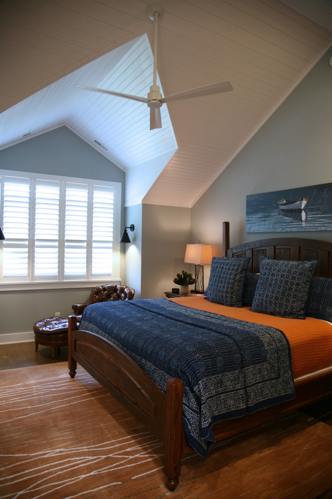 Inspiration for a mid-sized beach style guest bedroom in Milwaukee with blue walls, medium hardwood floors, brown floor, vaulted and wood walls.