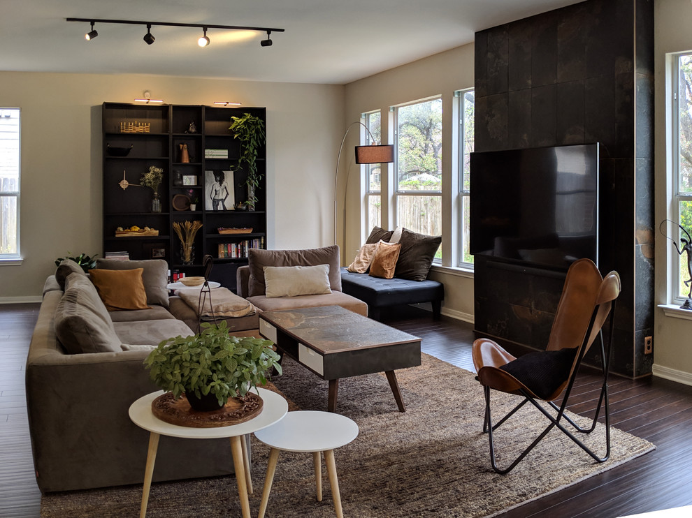 This is an example of a large modern open concept living room in Austin with black walls, dark hardwood floors, no fireplace and a wall-mounted tv.