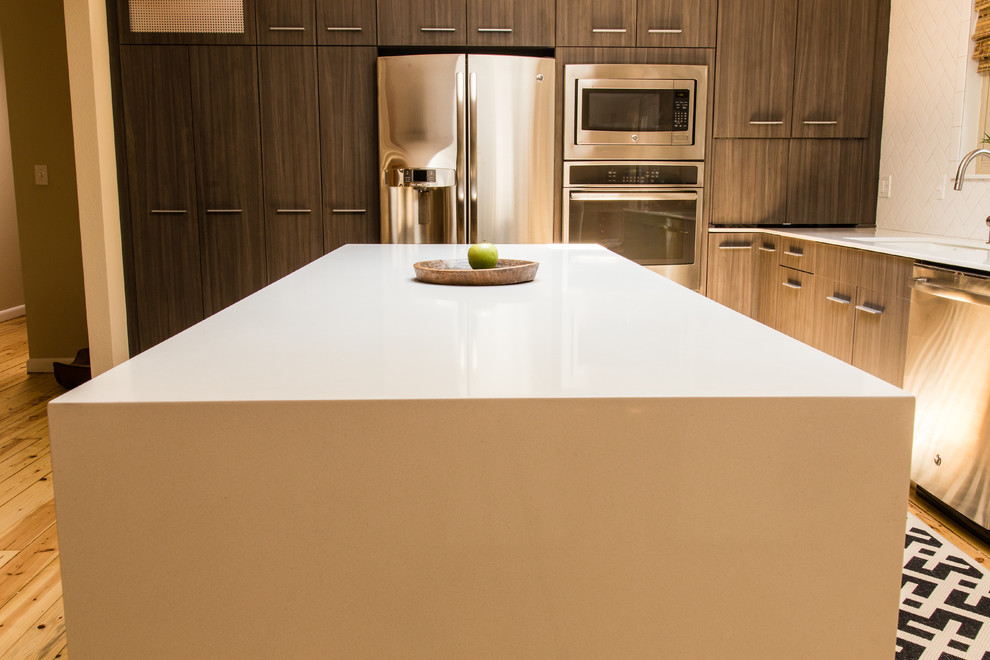 Mid-sized transitional l-shaped medium tone wood floor eat-in kitchen photo with quartz countertops, an undermount sink, flat-panel cabinets, dark wood cabinets, white backsplash, ceramic backsplash, stainless steel appliances and an island