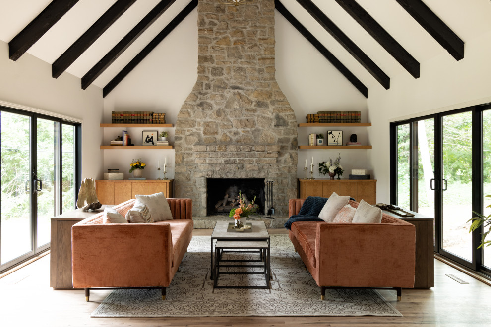 Inspiration for a contemporary open concept living room in Kansas City with white walls, light hardwood floors, a standard fireplace, a stone fireplace surround, no tv, brown floor and exposed beam.