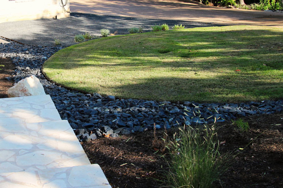 Design ideas for an expansive contemporary front yard driveway in Austin with with lawn edging and gravel.