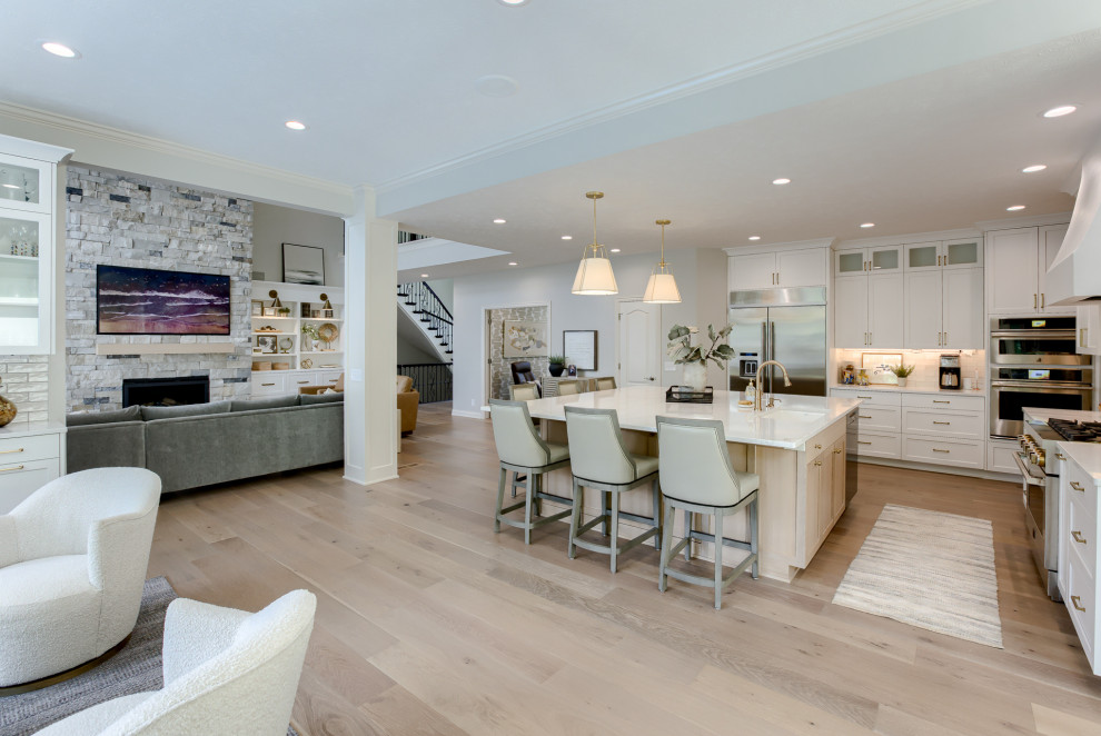 Transitional light wood floor and beige floor open concept kitchen photo with an undermount sink, white cabinets, quartzite countertops, multicolored backsplash, stainless steel appliances and an island