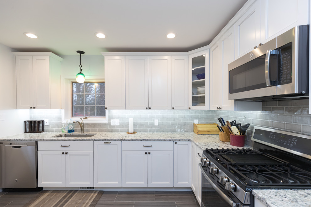 Example of a mid-sized transitional l-shaped porcelain tile and brown floor enclosed kitchen design in San Diego with an undermount sink, beaded inset cabinets, white cabinets, granite countertops, gray backsplash, ceramic backsplash, stainless steel appliances, no island and gray countertops