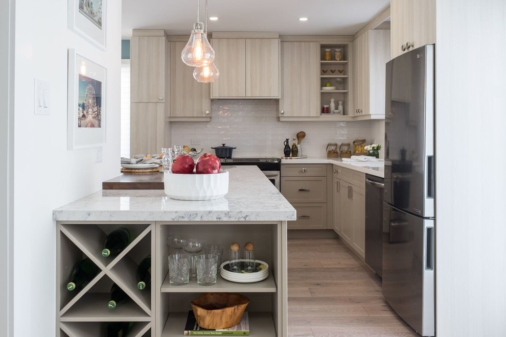 Design ideas for a small transitional l-shaped kitchen in Toronto with beige cabinets, white splashback, stainless steel appliances, light hardwood floors, marble benchtops, flat-panel cabinets, ceramic splashback, a peninsula, beige floor and white benchtop.