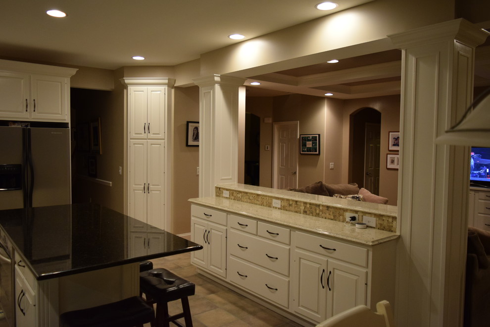 Inspiration for a transitional ceramic tile kitchen remodel with an undermount sink, raised-panel cabinets, quartz countertops, beige backsplash, ceramic backsplash, stainless steel appliances and an island
