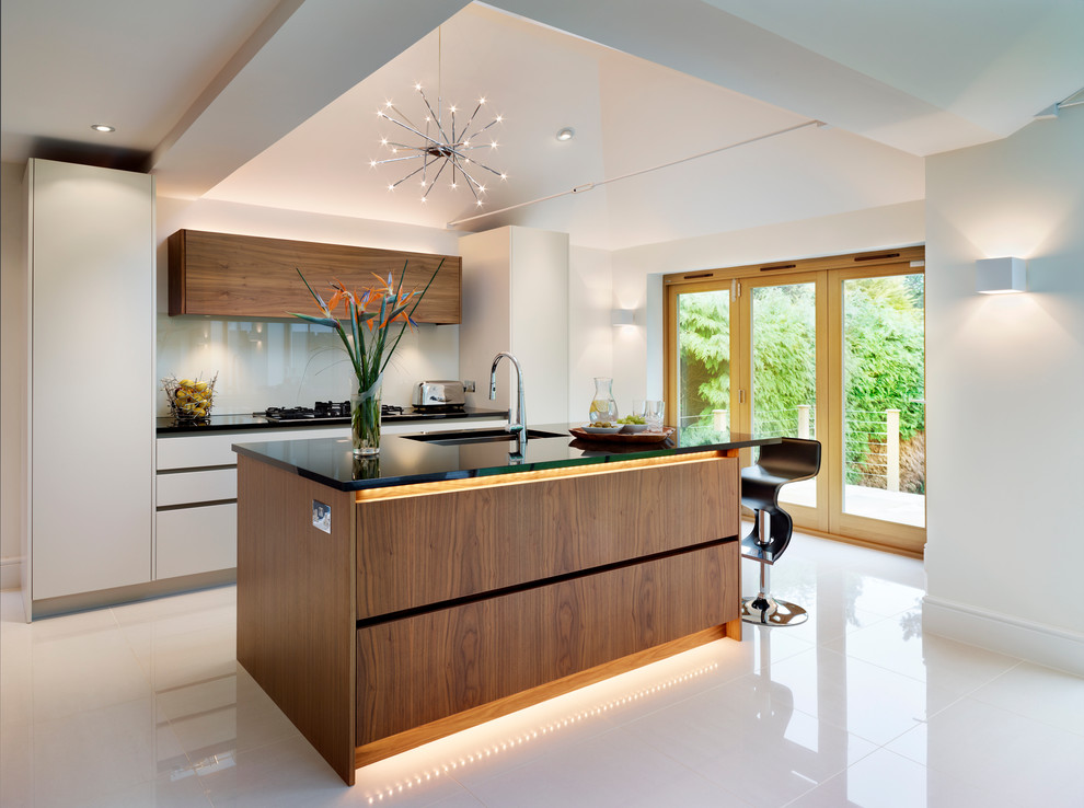 This is an example of a large contemporary open plan kitchen in London with flat-panel cabinets, medium wood cabinets, granite benchtops and with island.