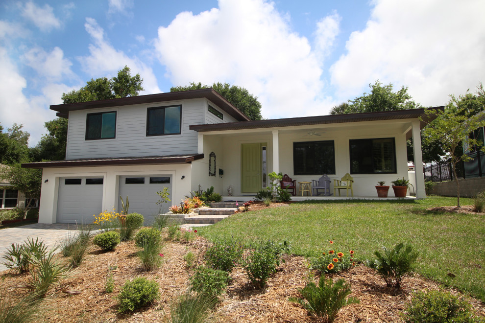 Mid-sized midcentury split-level grey house exterior in Orlando with mixed siding, a gable roof and a shingle roof.