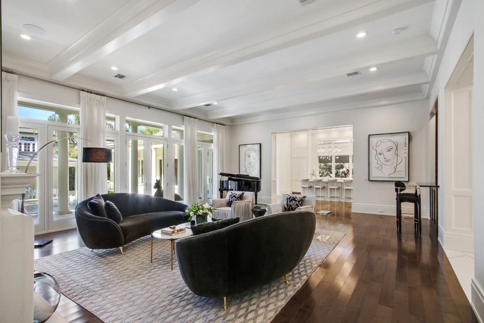This is an example of a large transitional formal open concept living room in New Orleans with white walls, medium hardwood floors, a standard fireplace, a plaster fireplace surround, no tv, brown floor and exposed beam.
