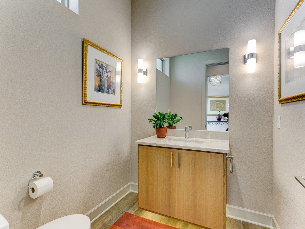 Bild på ett mellanstort funkis beige beige badrum, med släta luckor, skåp i ljust trä, en toalettstol med separat cisternkåpa, beige väggar, mellanmörkt trägolv, ett undermonterad handfat och granitbänkskiva