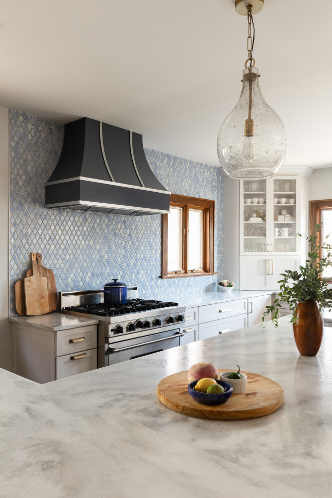 Large transitional l-shaped medium tone wood floor, brown floor and exposed beam open concept kitchen photo in Chicago with a farmhouse sink, shaker cabinets, blue cabinets, quartzite countertops, blue backsplash, ceramic backsplash, stainless steel appliances, an island and gray countertops