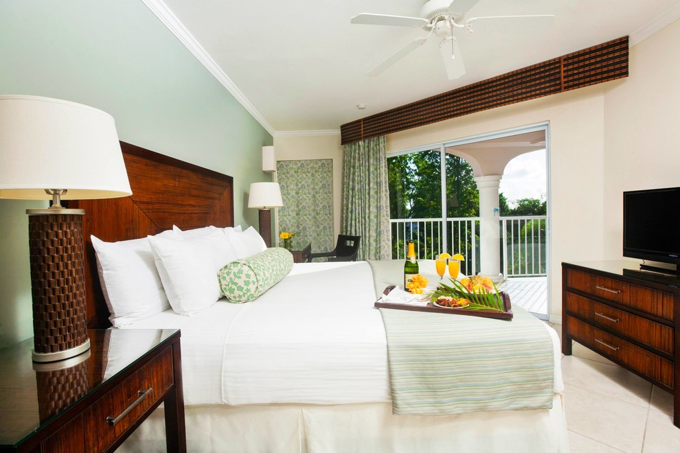 Photo of a mid-sized beach style guest bedroom in Other with green walls and travertine floors.