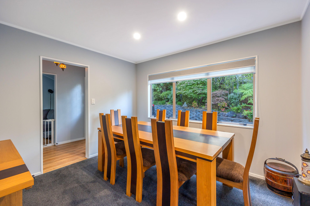 Foto di una grande sala da pranzo aperta verso il soggiorno minimalista con pareti grigie, moquette e pavimento grigio