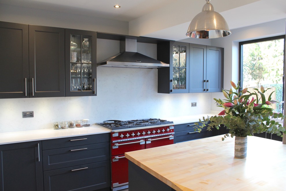 Photo of a mid-sized eclectic l-shaped open plan kitchen in London with a drop-in sink, shaker cabinets, black cabinets, quartzite benchtops, grey splashback, coloured appliances, vinyl floors, with island and brown floor.