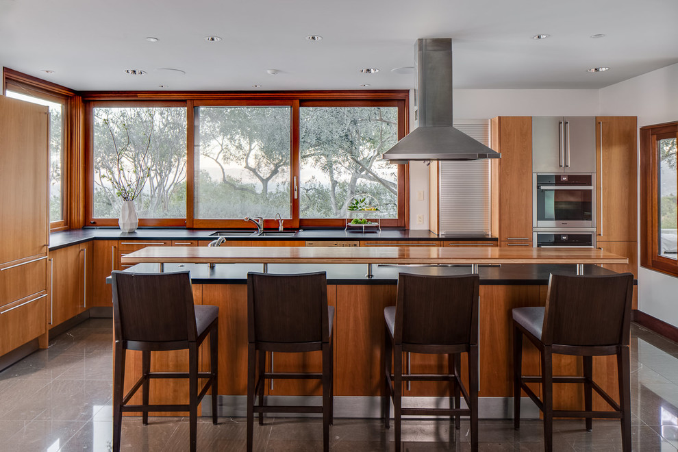 Photo of a large contemporary l-shaped open plan kitchen in San Francisco with flat-panel cabinets, medium wood cabinets, granite benchtops, with island, an undermount sink and panelled appliances.