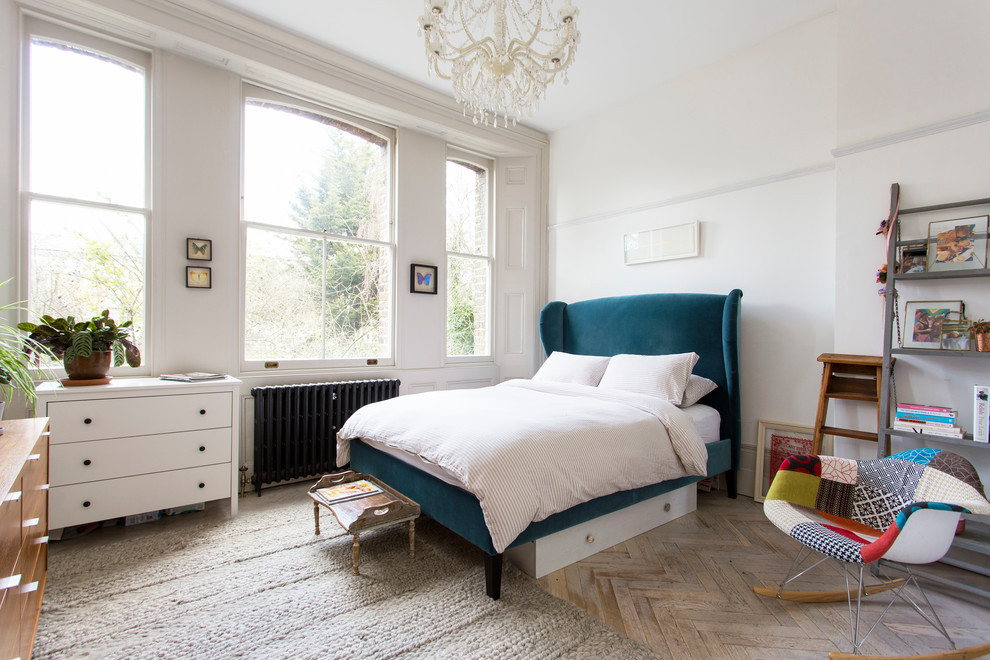 Mid-sized eclectic guest bedroom in London with white walls, light hardwood floors and white floor.