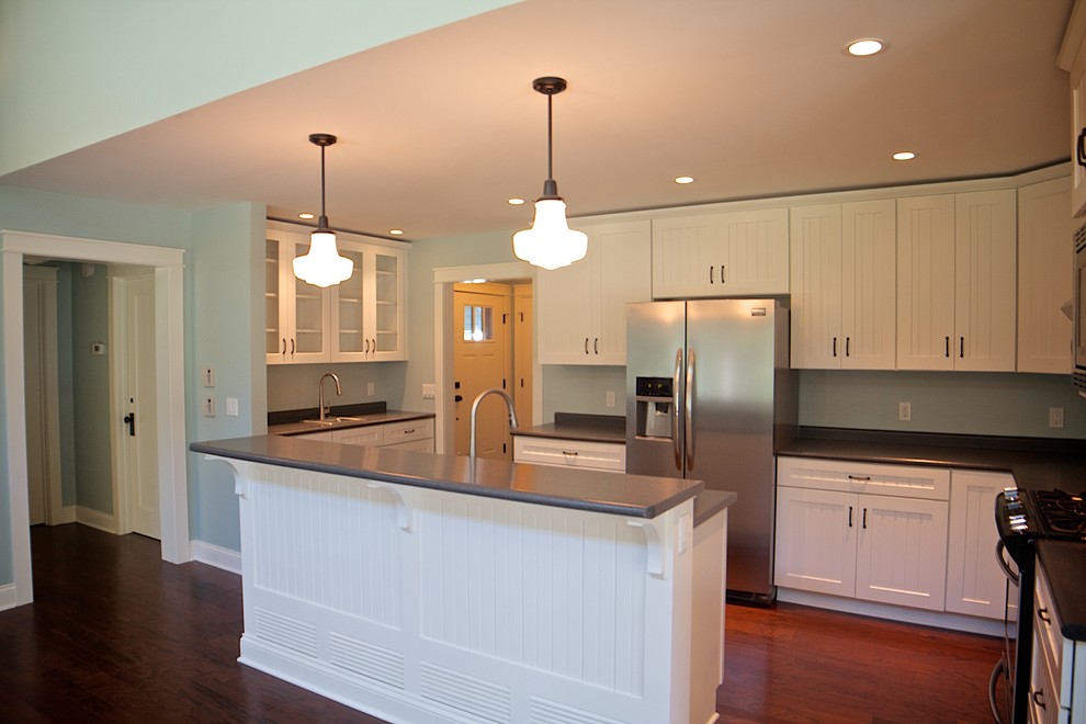 This is an example of a small transitional l-shaped eat-in kitchen in Other with beaded inset cabinets, white cabinets, laminate benchtops, stainless steel appliances, dark hardwood floors and with island.