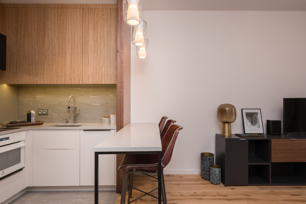 Small eclectic l-shaped separate kitchen in Other with a drop-in sink, flat-panel cabinets, white cabinets, quartzite benchtops, grey splashback, ceramic splashback, white appliances, ceramic floors, with island, grey floor and grey benchtop.