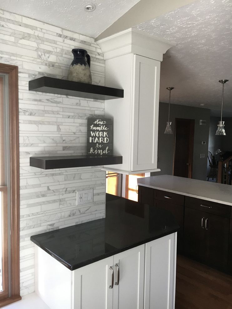 Inspiration for a large transitional single-wall medium tone wood floor eat-in kitchen remodel with an undermount sink, shaker cabinets, white cabinets, granite countertops, multicolored backsplash, marble backsplash, stainless steel appliances, an island and black countertops