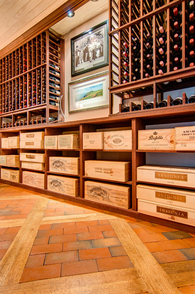 This is an example of a mid-sized traditional wine cellar in Other with brick floors and display racks.