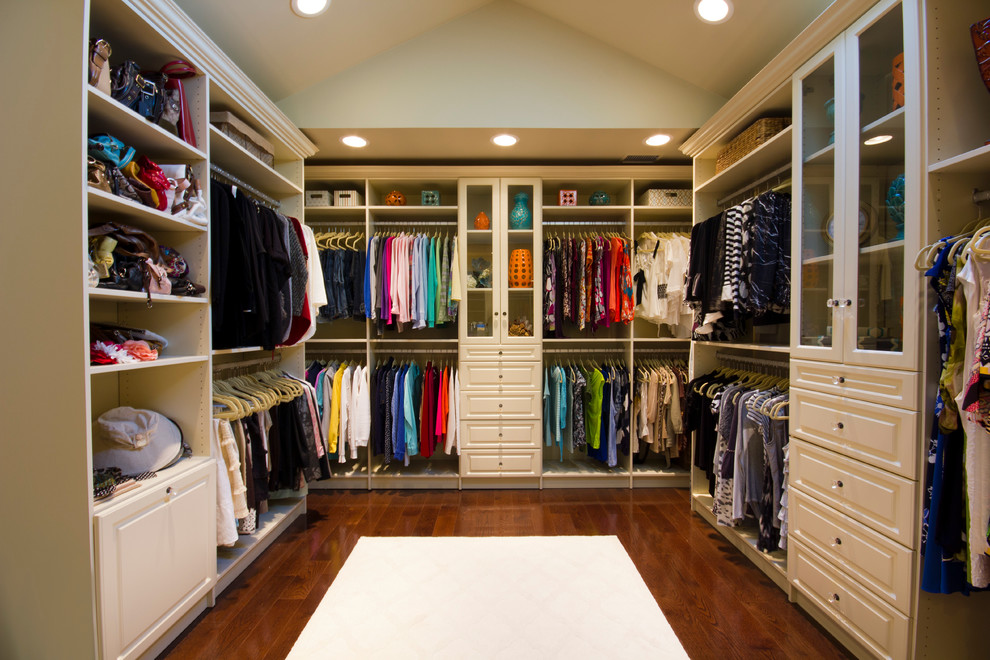 Inspiration for a large traditional women's walk-in wardrobe in New York with raised-panel cabinets, dark hardwood floors and white cabinets.