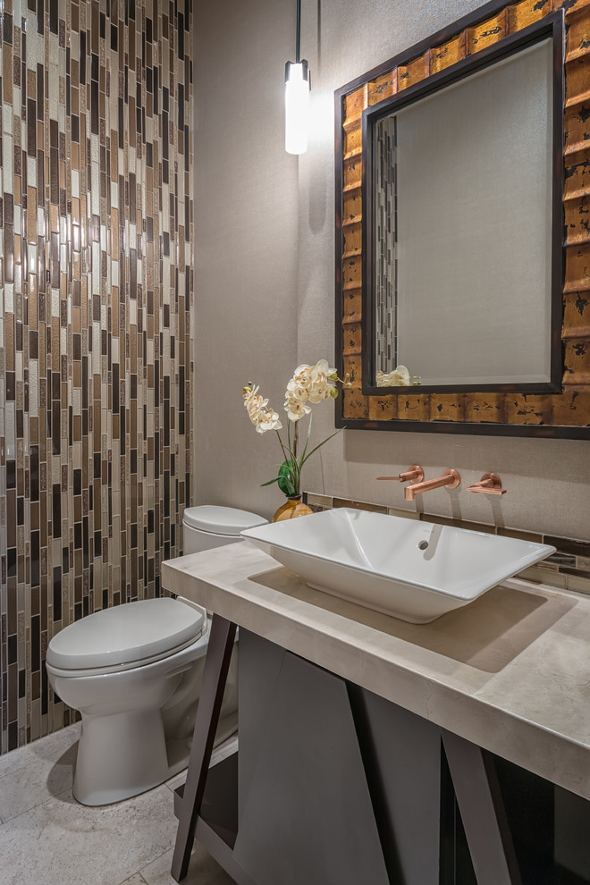 Inspiration for a small tropical powder room in San Diego with open cabinets, dark wood cabinets, a two-piece toilet, beige tile, glass tile, beige walls, travertine floors, a vessel sink and engineered quartz benchtops.