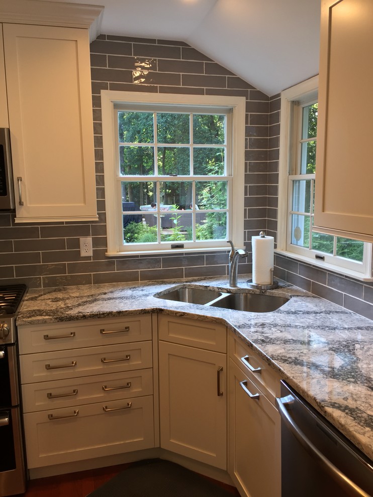 Mid-sized transitional u-shaped open plan kitchen in Baltimore with a double-bowl sink, shaker cabinets, white cabinets, quartz benchtops, grey splashback, ceramic splashback, stainless steel appliances, medium hardwood floors, no island, red floor and grey benchtop.