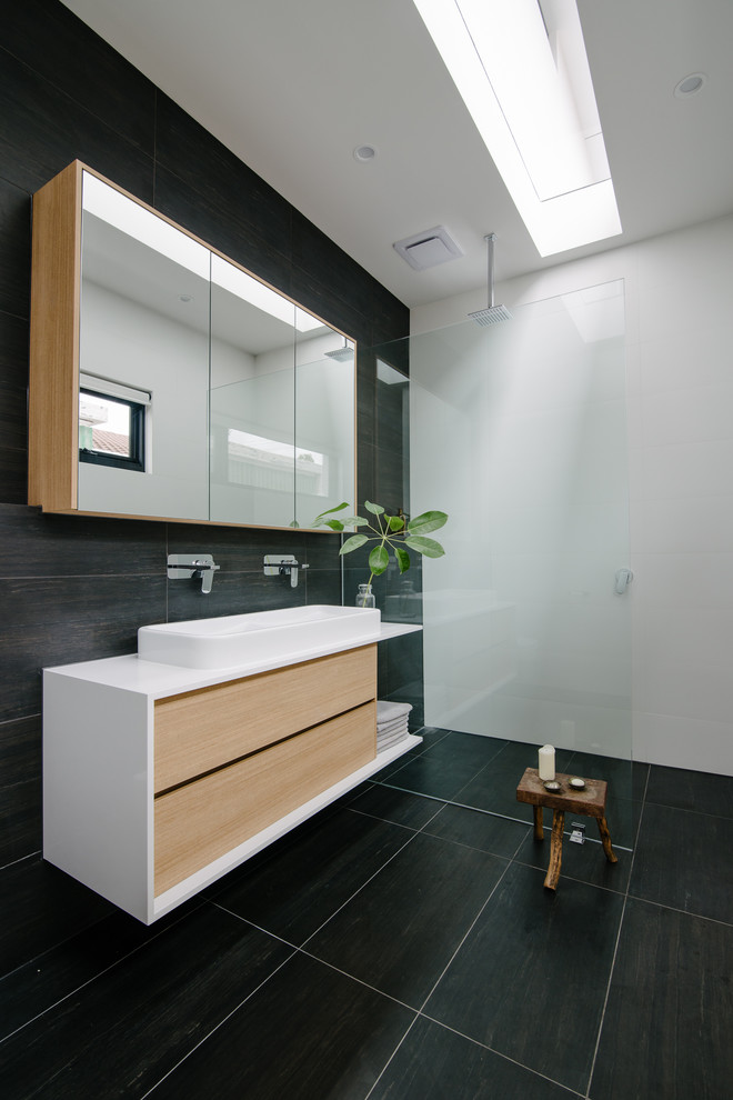 Mid-sized contemporary master bathroom in Adelaide with a vessel sink, flat-panel cabinets, light wood cabinets, engineered quartz benchtops, a curbless shower, black tile, porcelain tile, white walls, porcelain floors and white benchtops.