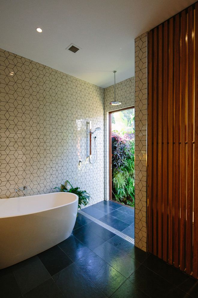 This is an example of a mid-sized contemporary bathroom in Sydney with an open shower, a japanese tub, an open shower, white tile, white walls and black floor.