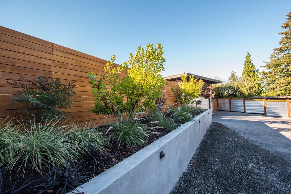 Photo of a mid-sized midcentury front yard driveway in Seattle with a retaining wall and concrete pavers.