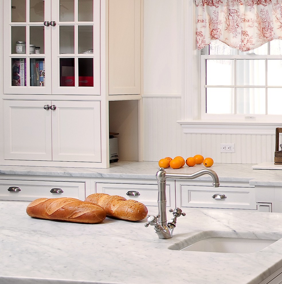 This is an example of a mid-sized traditional u-shaped kitchen in New York with a farmhouse sink, beaded inset cabinets, white cabinets, marble benchtops, white splashback, subway tile splashback, stainless steel appliances, dark hardwood floors and with island.