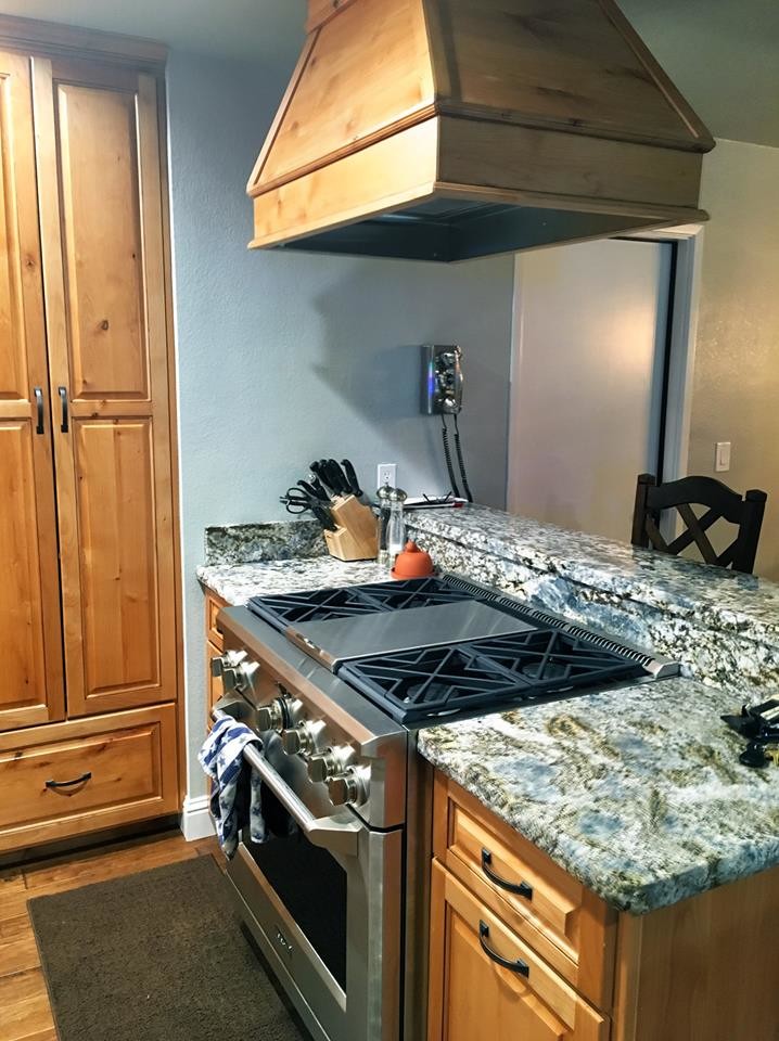 Example of a mid-sized mountain style u-shaped dark wood floor and brown floor enclosed kitchen design with a farmhouse sink, raised-panel cabinets, dark wood cabinets, quartz countertops, white backsplash, subway tile backsplash, stainless steel appliances and a peninsula