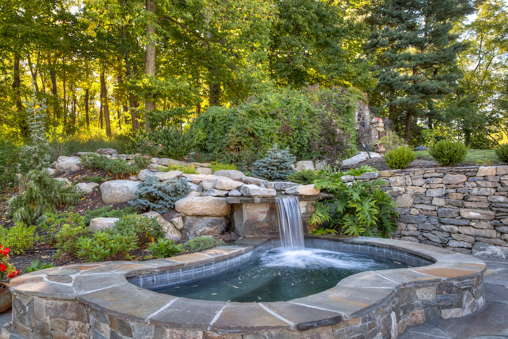 This is an example of a small traditional backyard kidney-shaped natural pool in New York with a hot tub and natural stone pavers.