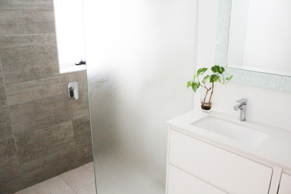 Photo of a mid-sized modern 3/4 bathroom in Perth with flat-panel cabinets, white cabinets, an open shower, a one-piece toilet, gray tile, porcelain tile, white walls, porcelain floors, a vessel sink, engineered quartz benchtops, grey floor, an open shower and white benchtops.