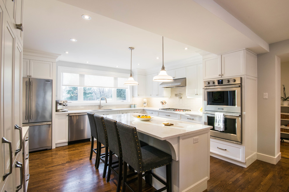 Inspiration for an expansive transitional l-shaped eat-in kitchen in Montreal with shaker cabinets, white cabinets, quartz benchtops, with island and white benchtop.