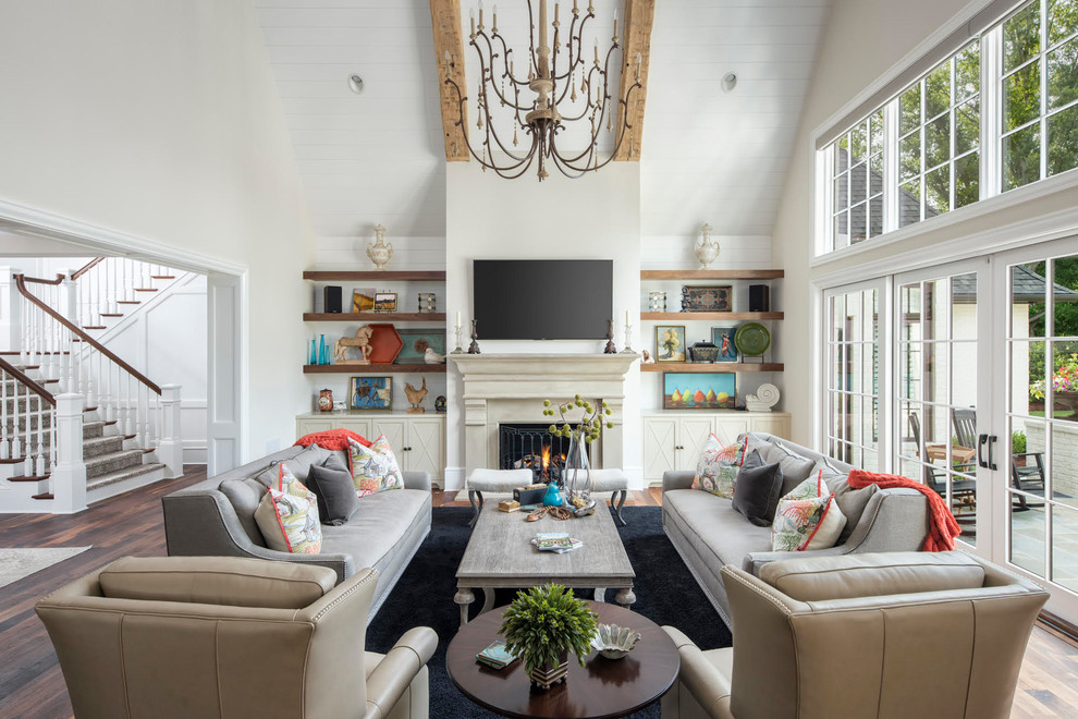 This is an example of a large country open concept living room in Charlotte with beige walls, medium hardwood floors, a standard fireplace, a plaster fireplace surround, a wall-mounted tv and brown floor.