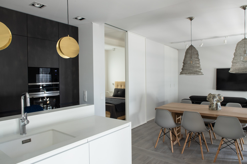 Photo of a mid-sized contemporary l-shaped open plan kitchen in Barcelona with an undermount sink, recessed-panel cabinets, white cabinets, quartz benchtops, white splashback, panelled appliances, porcelain floors, no island, grey floor and white benchtop.