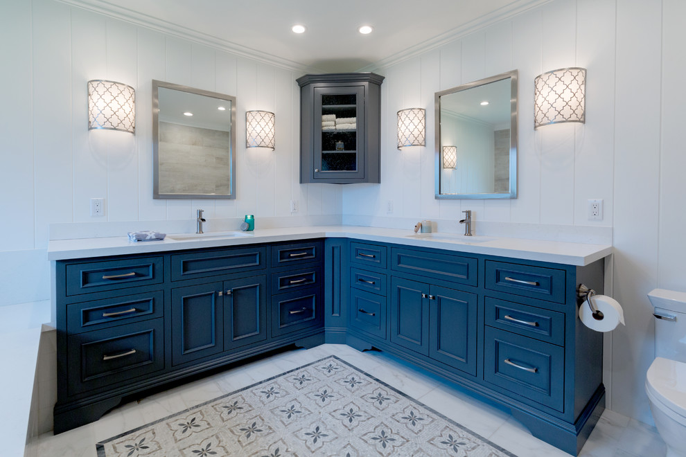 Design ideas for a mid-sized country master bathroom in San Francisco with recessed-panel cabinets, blue cabinets, an alcove tub, a shower/bathtub combo, a one-piece toilet, white walls, marble floors, an integrated sink, engineered quartz benchtops and white floor.