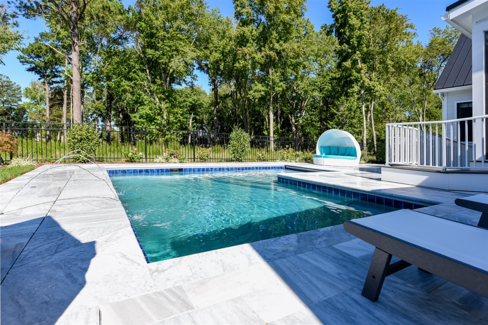 Immagine di una piscina stile marinaro a "L" di medie dimensioni e dietro casa con pavimentazioni in pietra naturale